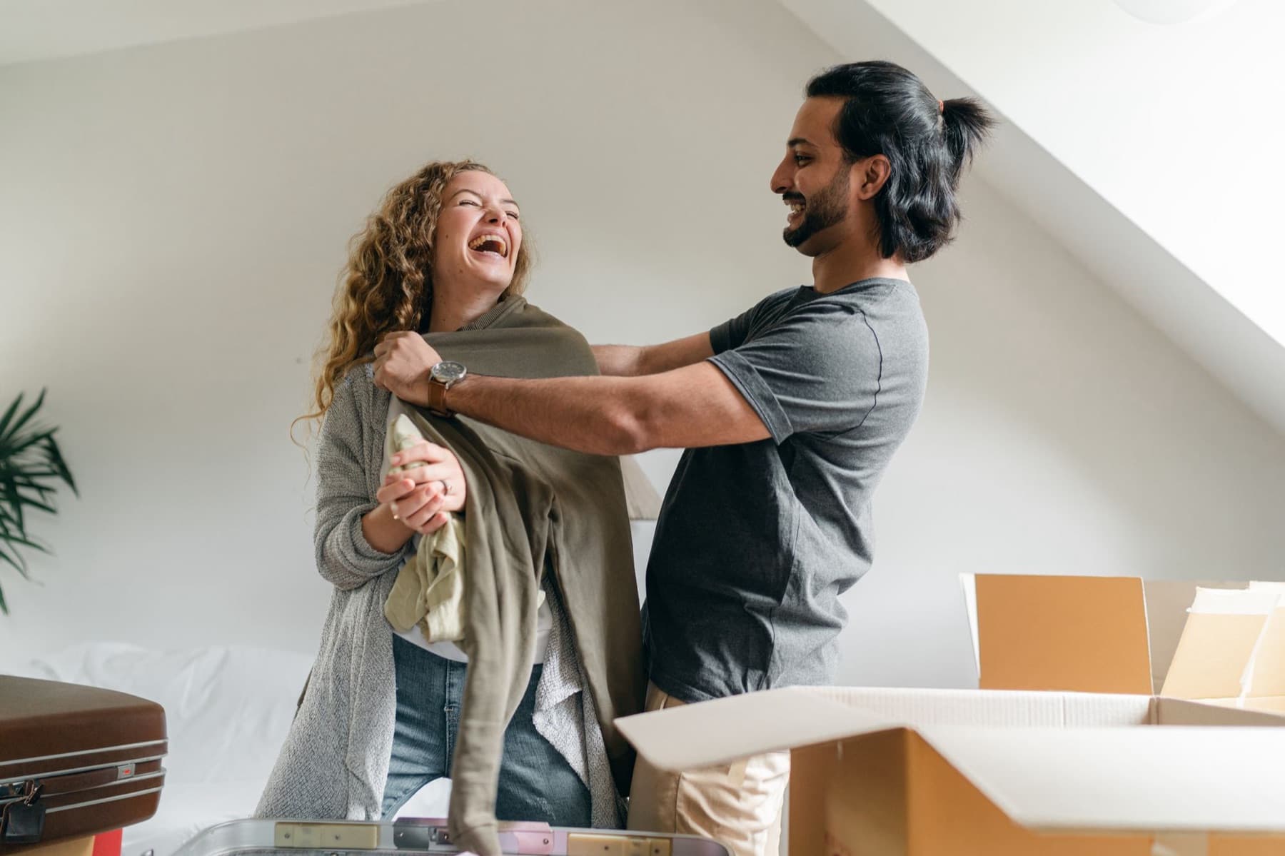 A couple laughing while unpacking moving boxes in their new place