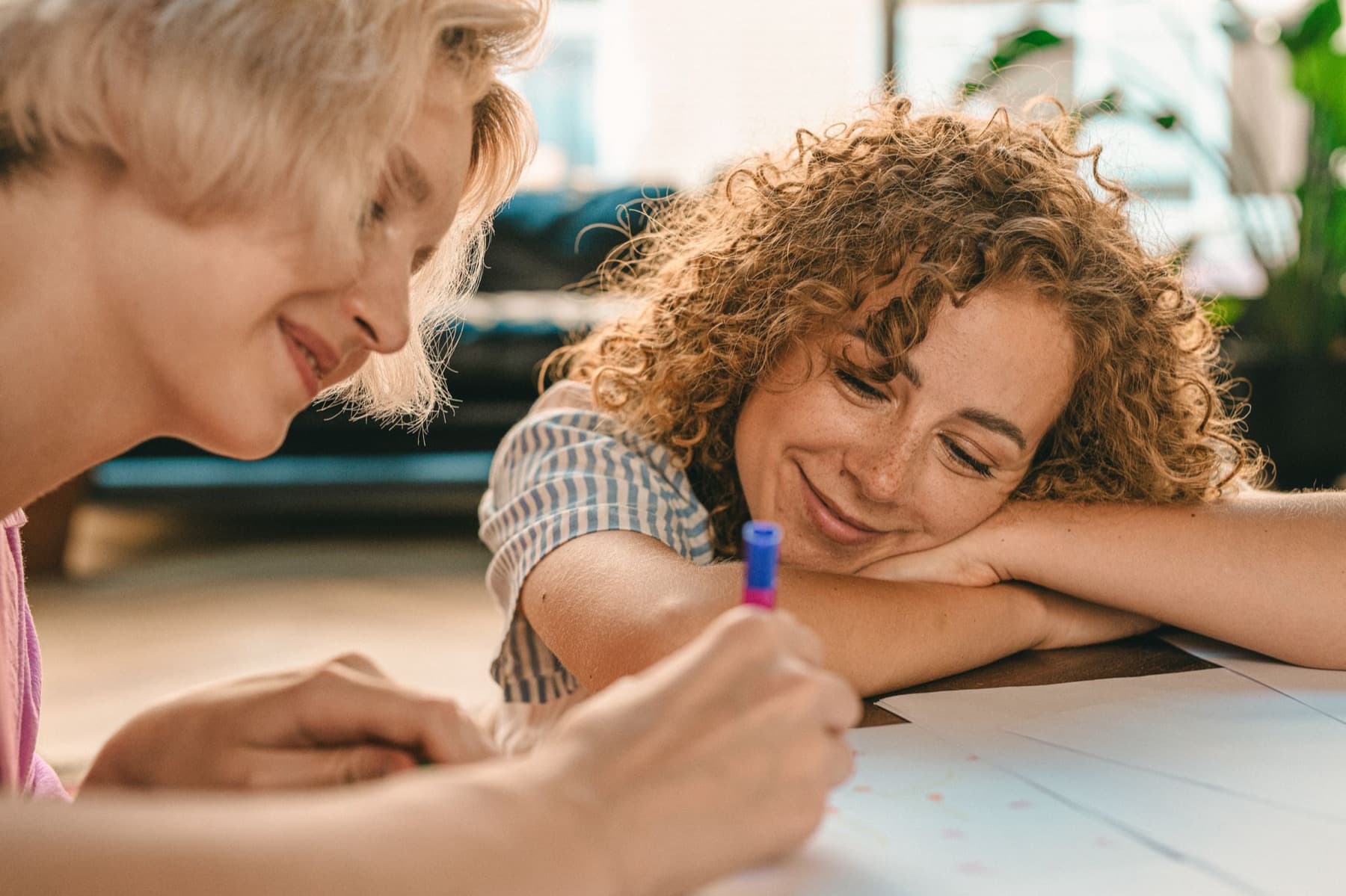 Two partners laughing while one writes at a table