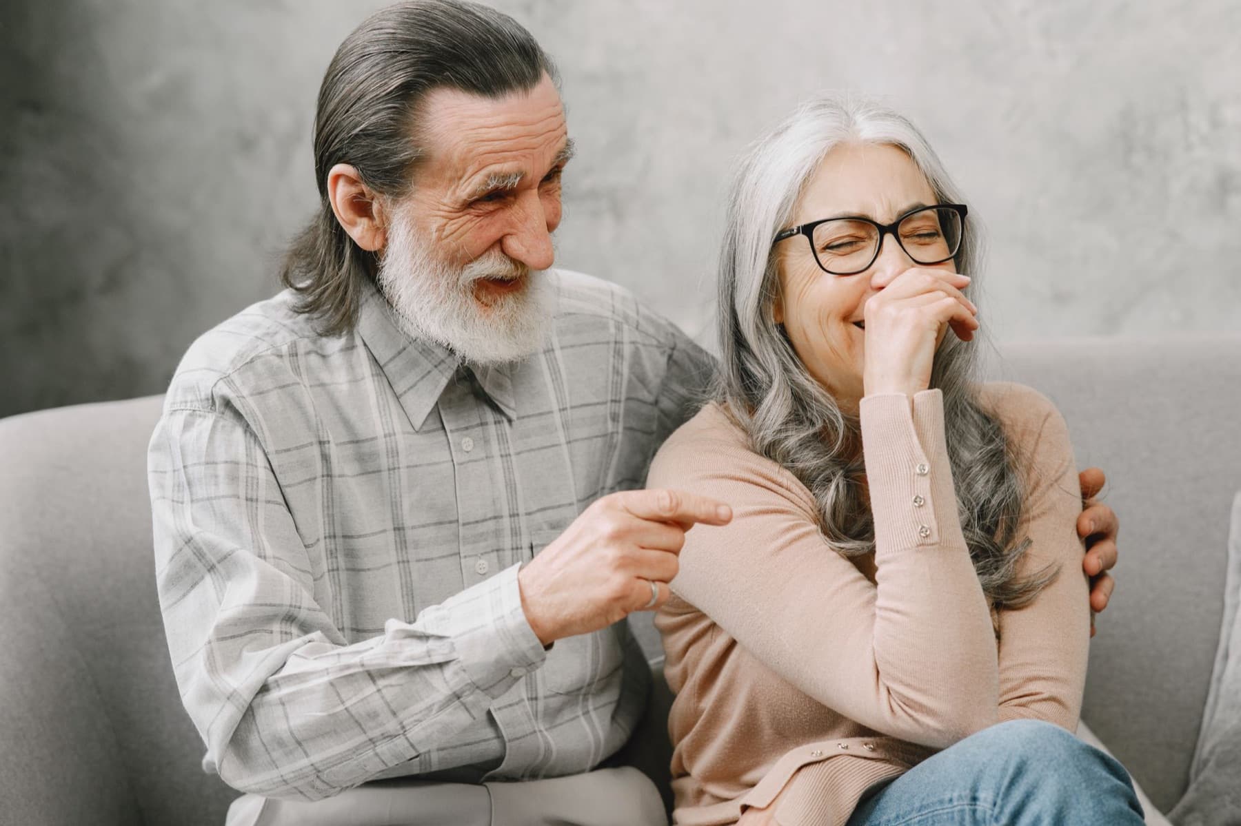 An older couple laughing together on the couch